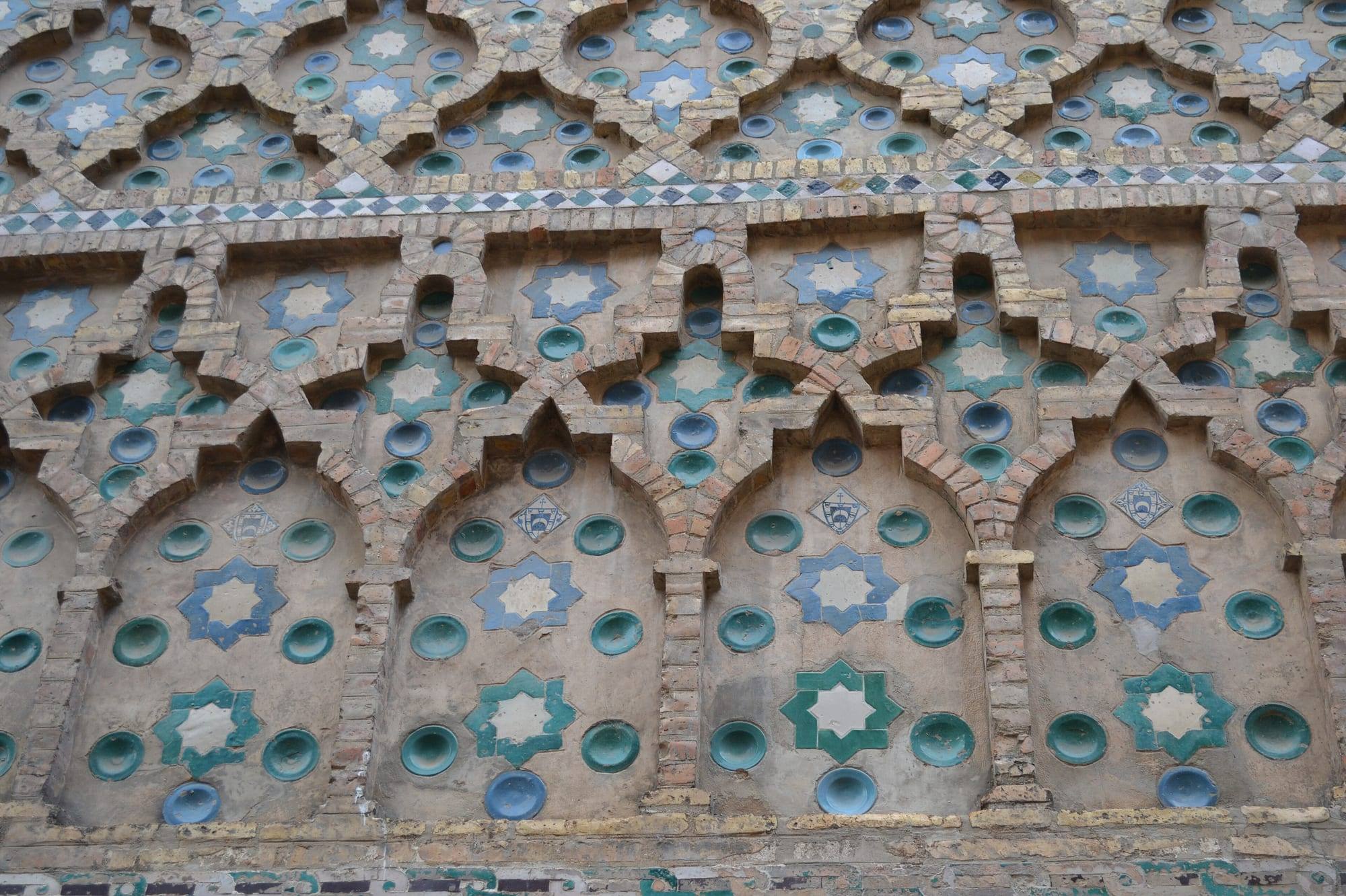 Close-up of the mudéjar decoration of the Parroquieta wall of La Seo cathedral in Zaragoza: interlaced brick arches set with green and blue glazed ceramic stars and discs